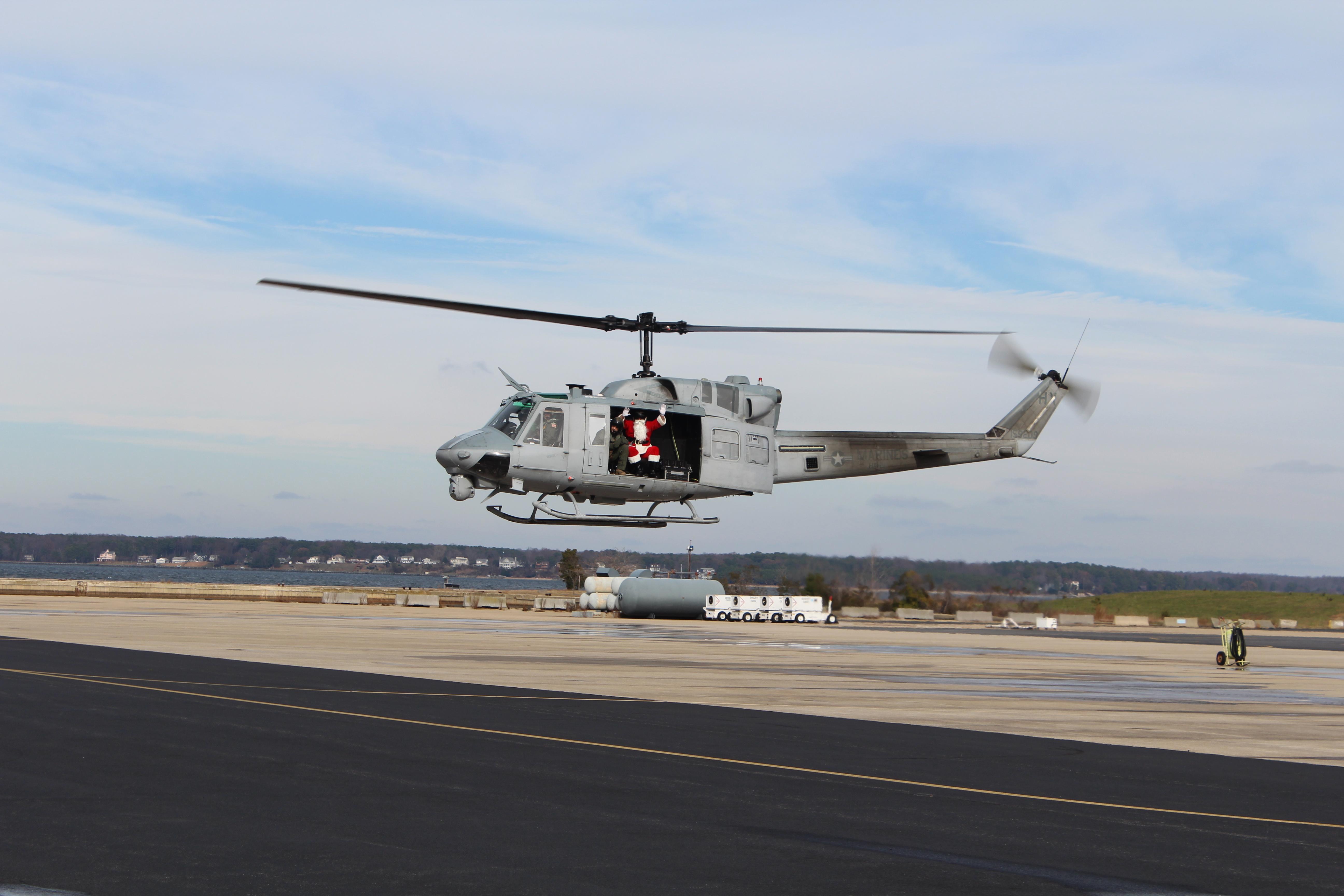 Adm. Claus waves from a helicopter near the Patuxent River in a red specialty flight suit.