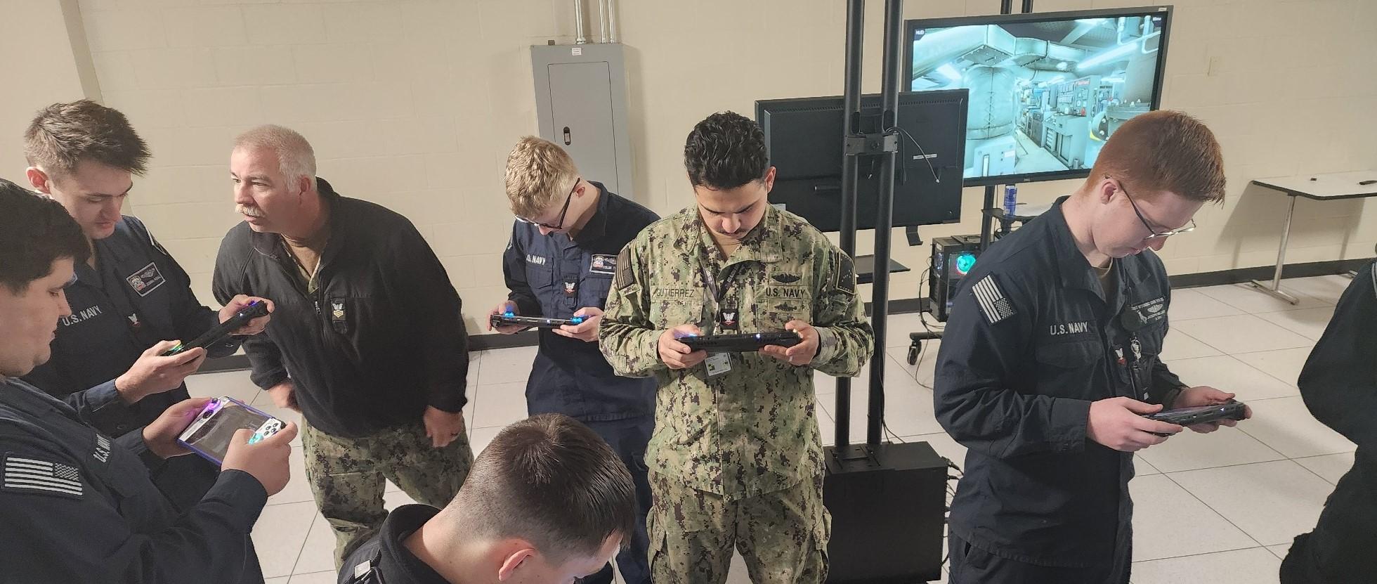 A group of students in military uniforms use a handheld training device