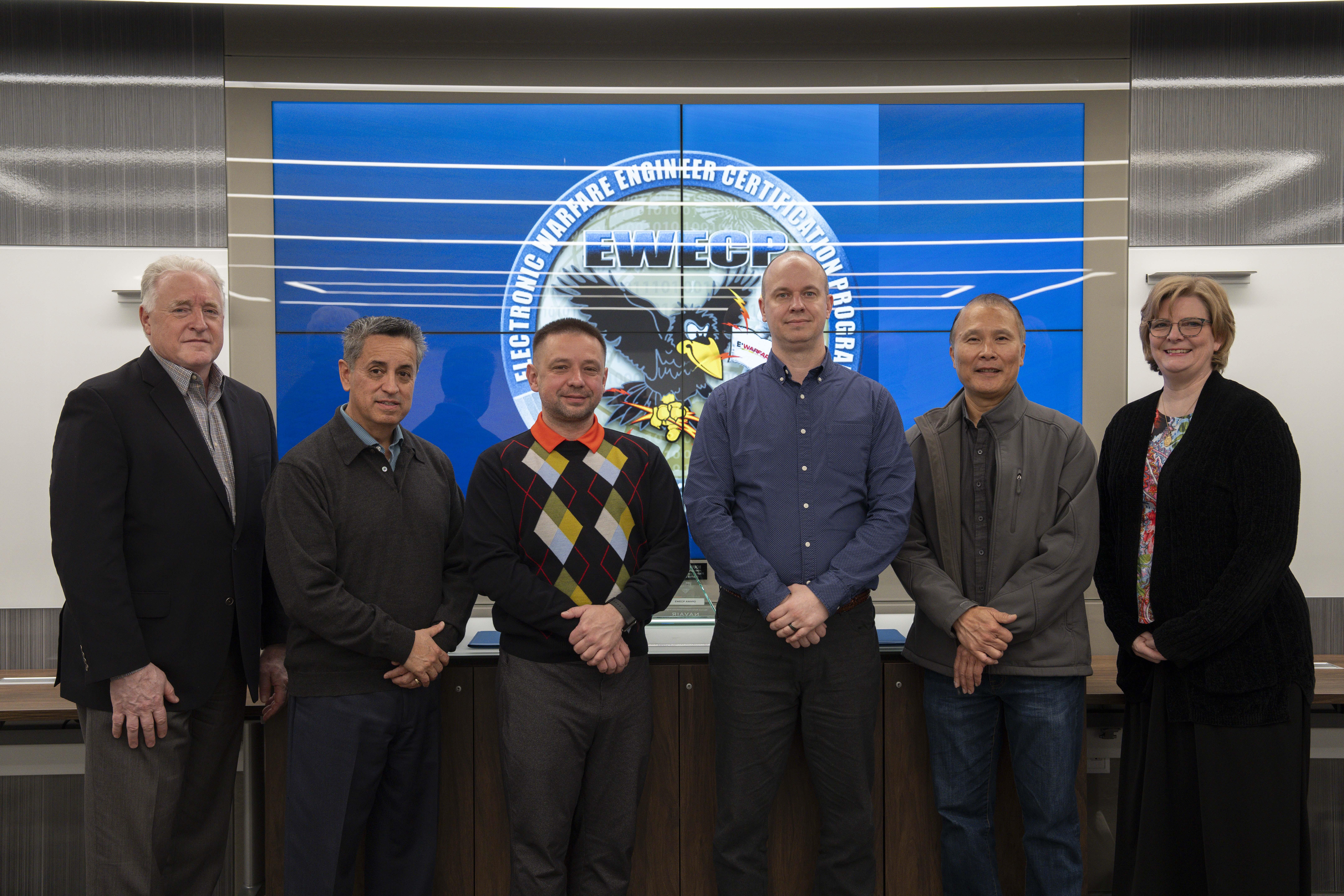 Electronic Warfare Engineering Certificate Program graduates, Pavel Rybakov (third from left) and Michael Fischer (third from right), pose with the program leaders and training coordinator in honor of their completion of the four-year curriculum during a ceremony in China Lake on Jan. 21. 