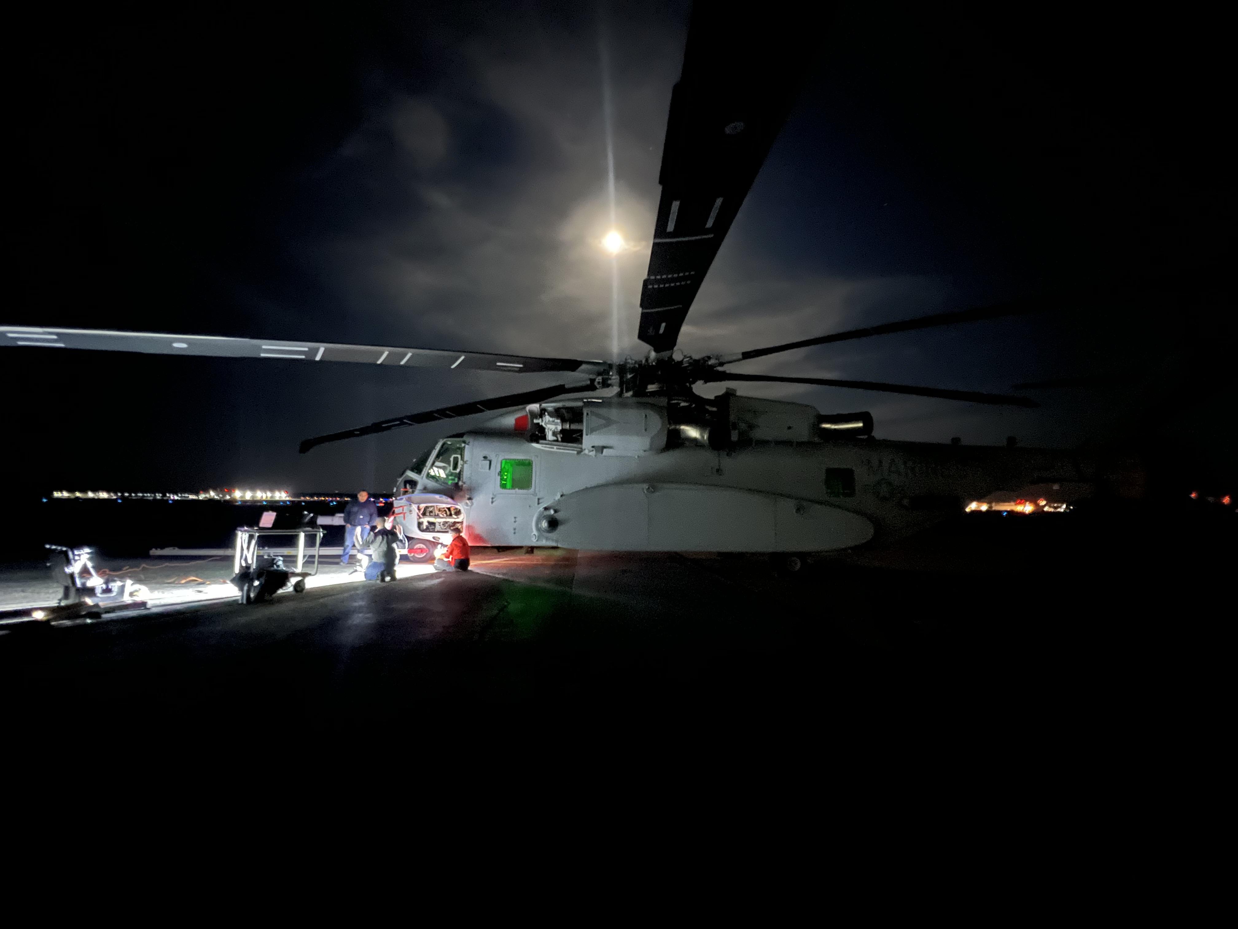 Helicopter sits on a dark runway with the moon shining overhead