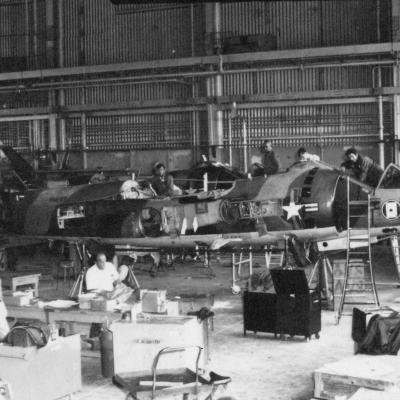 black and white photo of artisans working on old AV-8 Harrier aircraft