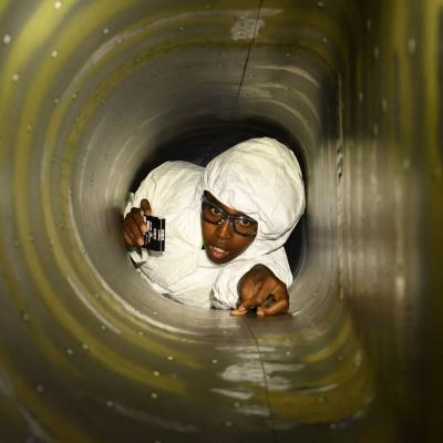 A mechanical engineer at Fleet Readiness Center Southeast (FRCSE), applies positioning targets to the inside of an F-5N engine air intake before 3D scanning. 