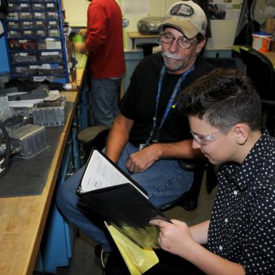 High school students looks at technical data manual for aircraft component