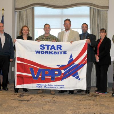 FRCE leadership poses with the VPP Star Worksite flag.