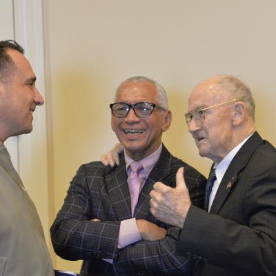 Naval Test Wing Atlantic commander, Col. Richard E. Marigliano, left, and retired Maj. Gen. Charles Bolden, former astronaut and NASA administrator, center, laugh as retired Lt. Cmdr. Harry Errington recalls a story prior to the air wing’s annual awards luncheon for 2019 honorees.