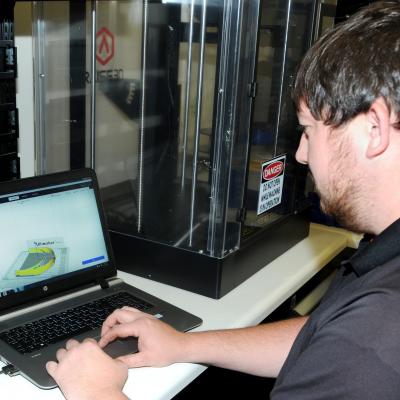 Innovation lead Randall Lewis uses a computer-aided design file to 3D print face shield headbands