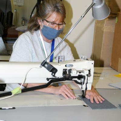 Woman uses sewing machine to make cloth face covering