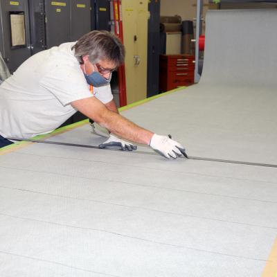 Man uses straight edge to cut fabric for cloth face coverings