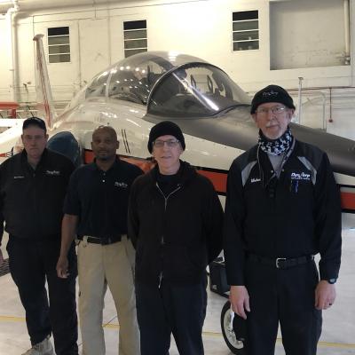 U.S. Naval Test Pilot School maintenance team members (from left to right) Mearland “Zeke” Rusaw, Lenny Epps, Danny Breedlove, and Michael Lopshire solved a problem that had been plaguing the operators of the T-38 Talon twin-engined supersonic trainer for two decades. Their solution is expected to save the Navy, Air Force, and NASA $207 million and thousands of man-hours over the service life of the T-38. (Note that this photo was taken prior to the Department of Defense guidance on wearing face protection.