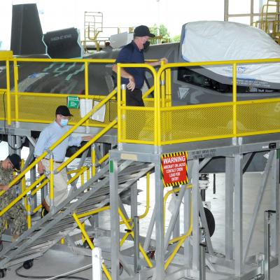 Three men climb stand to view F-35 aircraft