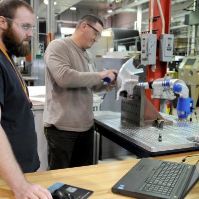 FRCE machinists measure a 522 fitting using a FaroArm