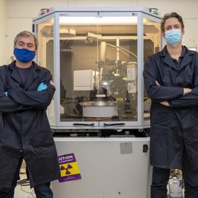 Dr. Randall McClain, left, and Dr. Ben Harvey stand in front of a single crystal X-ray diffractometer, which is used to determine the chemical structure of molecules. (U.S. Navy photo by Ryan Smith)