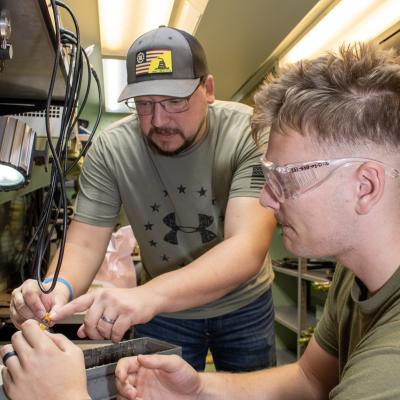 Civilian electronics integrated system mechanic explains F/A-18 Hornet circuit breaker panel to Marine.