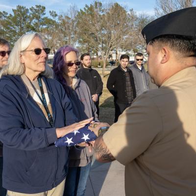 Surrounded by family and friends, Debbie Covey (left) is presented with a flag in honor of nearly 50 years of service to the government during a ceremony Jan.  28 in China Lake, Calif. (U.S. Navy photo by Ryan Smith) 