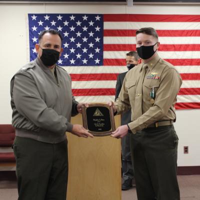 Col. Richard E. Marigliano, commander of Naval Test Wing Atlantic (NTWL), left, presents Air Test and Evaluation Squadron (HX) 21 pilot Maj. Joshua Foxton with NTWL's Test Pilot of the Year award for 2020 during a ceremony on February 12 2021.