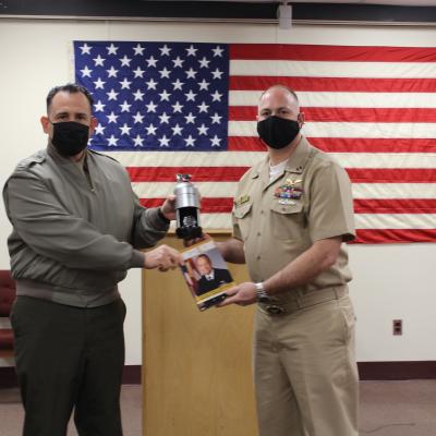 Col. Richard E. Marigliano, commander of Naval Test Wing Atlantic (NTWL), left, presents Air Test and Evaluation Squadron (HX) 21 maintenance officer Lt. Brandon Merchant with NTWL's Maintenance Officer of the Year award for 2020 during a ceremony on February 12 2021.