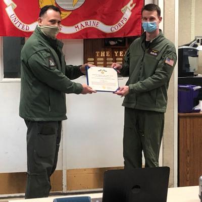 Cmdr. Daniel P. Martin, commanding officer of Air Test and Evaluation Squadron (UX) 24, right, accepts the Navy and Marine Corps Commendation Medal from Col. Richard E. Marigliano, commanding officer of Naval Test Wing Atlantic (NTWL), on behalf of Maj. Joseph Davin, the 2020 NTWL Test Naval Flight Officer of the Year, during a virtual ceremony on March 5.