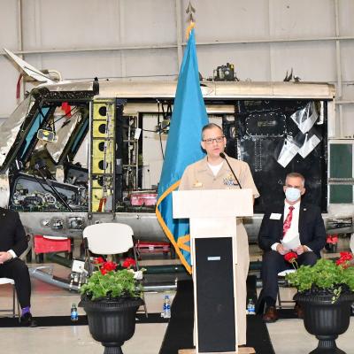 Navy captain and local dignitaries in front of H-1 helicopter airframe
