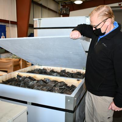 Man displays scrap parts in crate