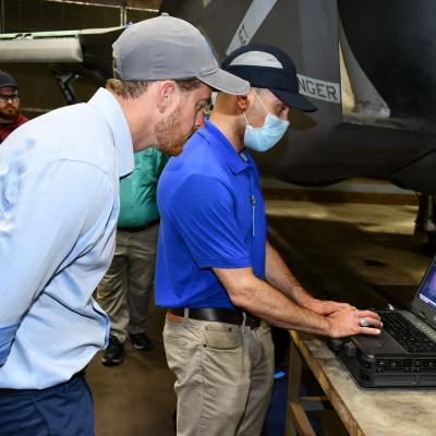 Men observe test on laptop