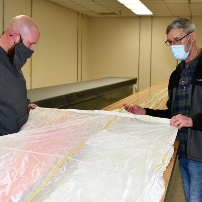 Kristopher Kirksey, a quality assurance specialist at Fleet Readiness Center East (FRCE), and Jeff Ellman, FRCE ordinance and survival shop work leader, inspect an ejection seat parachute for the F-35B Lightning II. FRCE has expanded its support of next-generation naval aviation by declaring capabilities on a new round of F-35 components including these parachutes. 