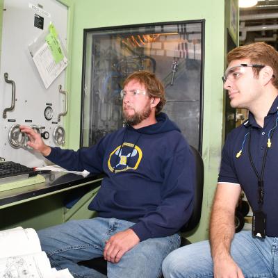 Shawn Kidney, left, a pneudralics systems mechanic at Fleet Readiness Center East (FRCE), and Wyatt Amacker, an aerospace engineer at the depot, test an AV-8B fuel management unit.