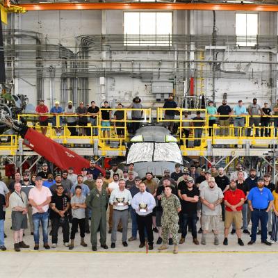Group poses in front of V-22 aircraft
