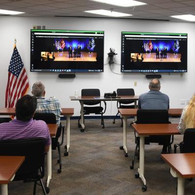Employees watching ceremony on monitors