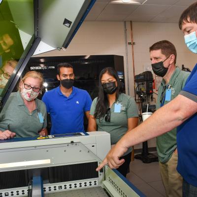 Fleet Readiness Center East (FRCE) Innovation Lead Engineer Randall Lewis, right, demonstrates the use of a 3D printer at the depot’s innovation lab to local educators during a four day externship program focused on preparing students for careers in industry. 