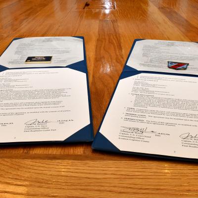 Two challenge coins sit on top of signed documents