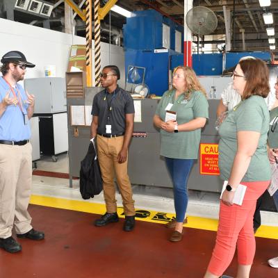 Fleet Readiness Center East (FRCE) Aerospace Engineer Sean Murphy, left, guides a tour of local educators through the depot’s H-53 line during a four day externship program focused on preparing students for careers in industry.
