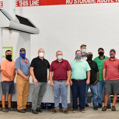 Personnel from Fleet Readiness Center East’s (FRCE) Precision Measurement Center stand for a group photo in front of a newly acquired coordinate measuring machine (CMM). This machine is one of two new CMMs FRCE acquired capable of large-volume measurement. Depot officials say the additional machines will improve efficiency and reduce wait times caused by maintenance and equipment calibration. 
