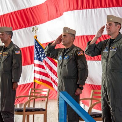NAVAIR's Vice Adm. Carl Chebi, outgoing Rear Adm. John Lemmon, and incoming Rear Adm. John Dougherty IV salute in front of the American flag.