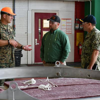 Maj. Gen. Scott F. Benedict, commanding general of 2nd Marine Aircraft Wing (MAW), left, discusses MV-22 stow rings with  Fleet Readiness Center East (FRCE) Commanding Officer Capt. James Belmont  and FRCE V-22 Branch Head Andrew Rock during an Aug. 30 tour of the depot by 2nd MAW leadership. 