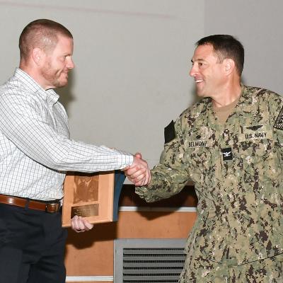 Navy captain shakes hand with civilian employee during award presentation