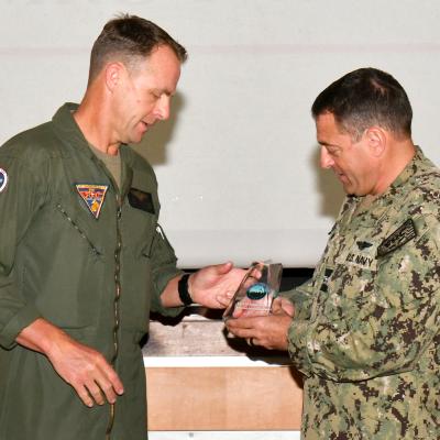 Navy captain passes award statuette to Marine lieutenant colonel