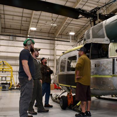 UH-1N helicopter maintainers and pilot discuss aircraft in hangar