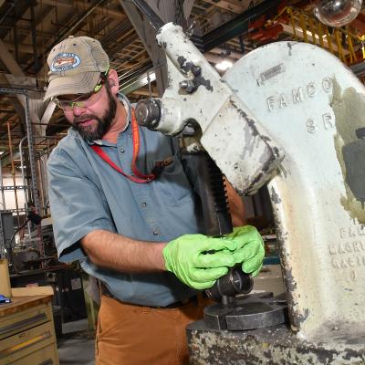 Jeremy Pedersen, machinist at Fleet Readiness Center East’s Repair Machine Shop, utilizes a press while working on an aircraft component. The Repair Machine Shop is made up of 22 work centers where 70 highly trained machinists recondition everything from helicopter transmissions to jet engine components. 