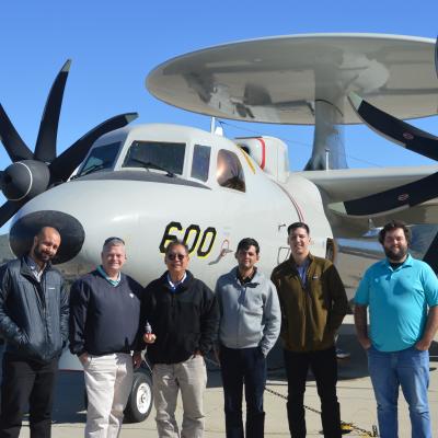 Group of people standing in front of E-2D aircraft.