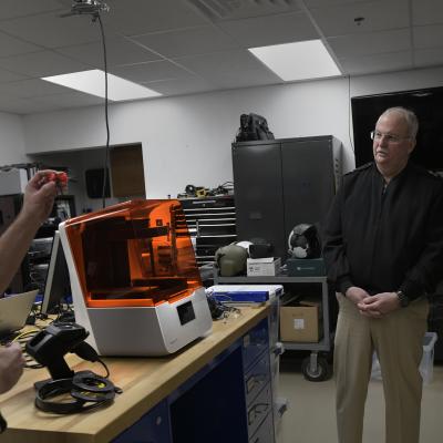 A naval officer demonstrates a process to use 3D printers and a digital scanner to produce custom ear plugs.
