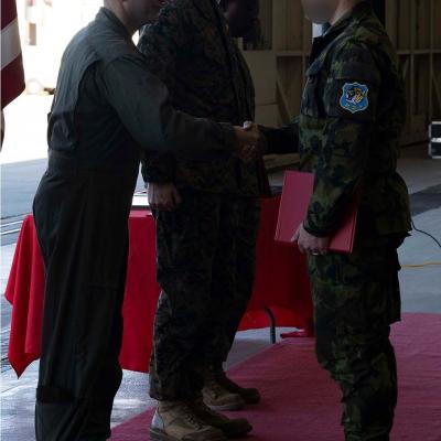 A Czech Air Force crew chief accepts his graduation certificate from U.S. Marine Corps Col. Vasilios E. Pappas