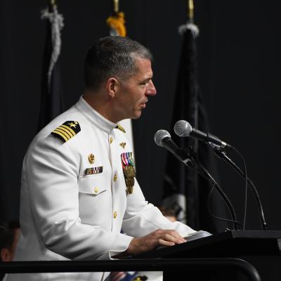Navy captain in uniform speaking at podium. 