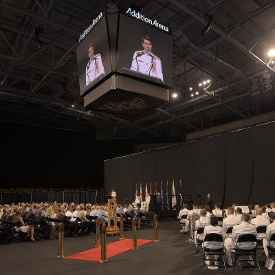People attend a Navy change of command ceremony in an athletic arena. 