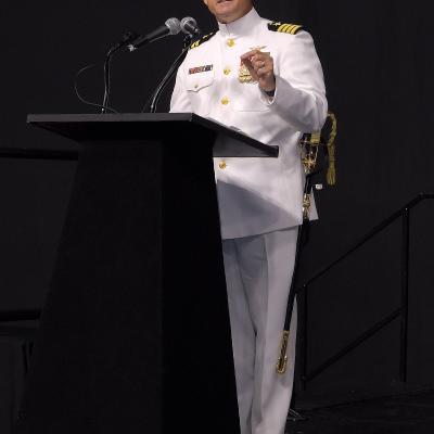 Navy officer speaking at podium.