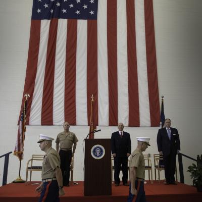 Two marines walk away from one another with a large flag in the background after officially changing command