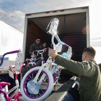 Man on right grabbing a children's bike to put into semi-trailer 