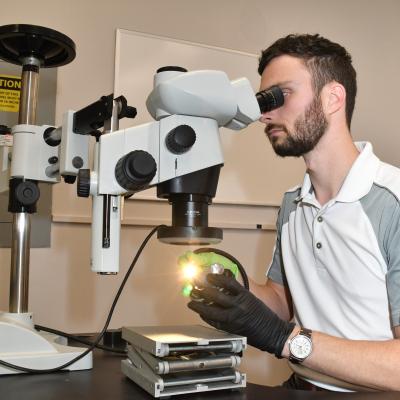 Latane Mason, a materials engineer at Fleet Readiness Center East’s (FRCE) Materials Engineering Division, examines a fractured surface using a stereo microscope. The Materials Engineering Division utilizes state of the art laboratory equipment to perform research, testing and evaluation activities as well as to develop and continually improve the processes in use within FRCE.