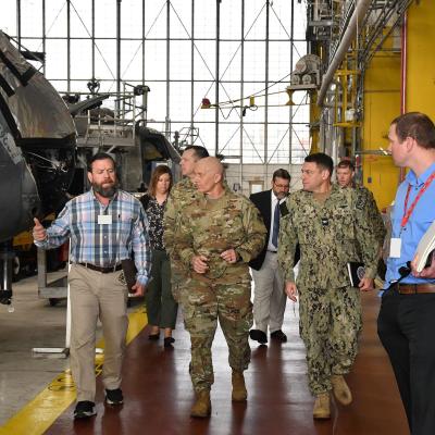 Group of military officials walks down aisle in aircraft hangar