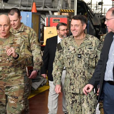 Group of military officials walks down aisle in aircraft hangar