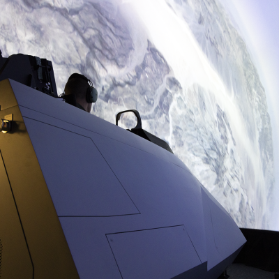 A cockpit sits in a domed simulator that with a global display.